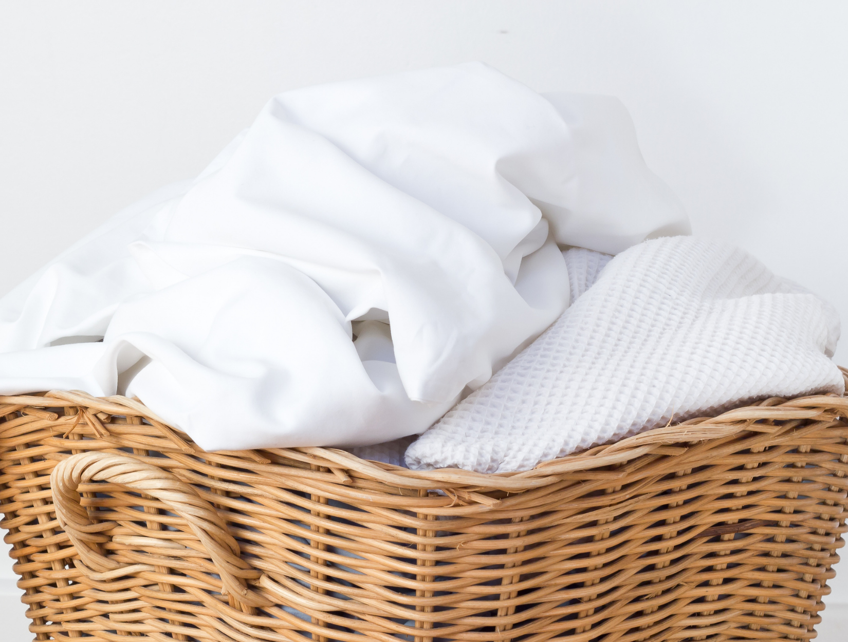 A basket of freshly laundered holiday cottage bedding and towels by Dryden Cottage Laundry Services